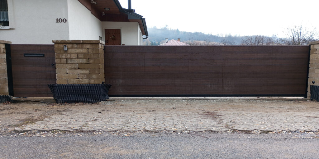 V obci Mýto pod Ďumbierom sme realizovali projekt samonosnej brány s plnou automatizáciou značky ROGER, vybavenej LED majákom, a bráničky s nerezovým kovaním, integrovanou poštovou schránkou a videovrátnikom.